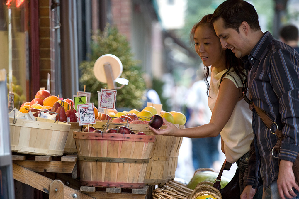 A man and woman couple looking at fruit at an outdoor market