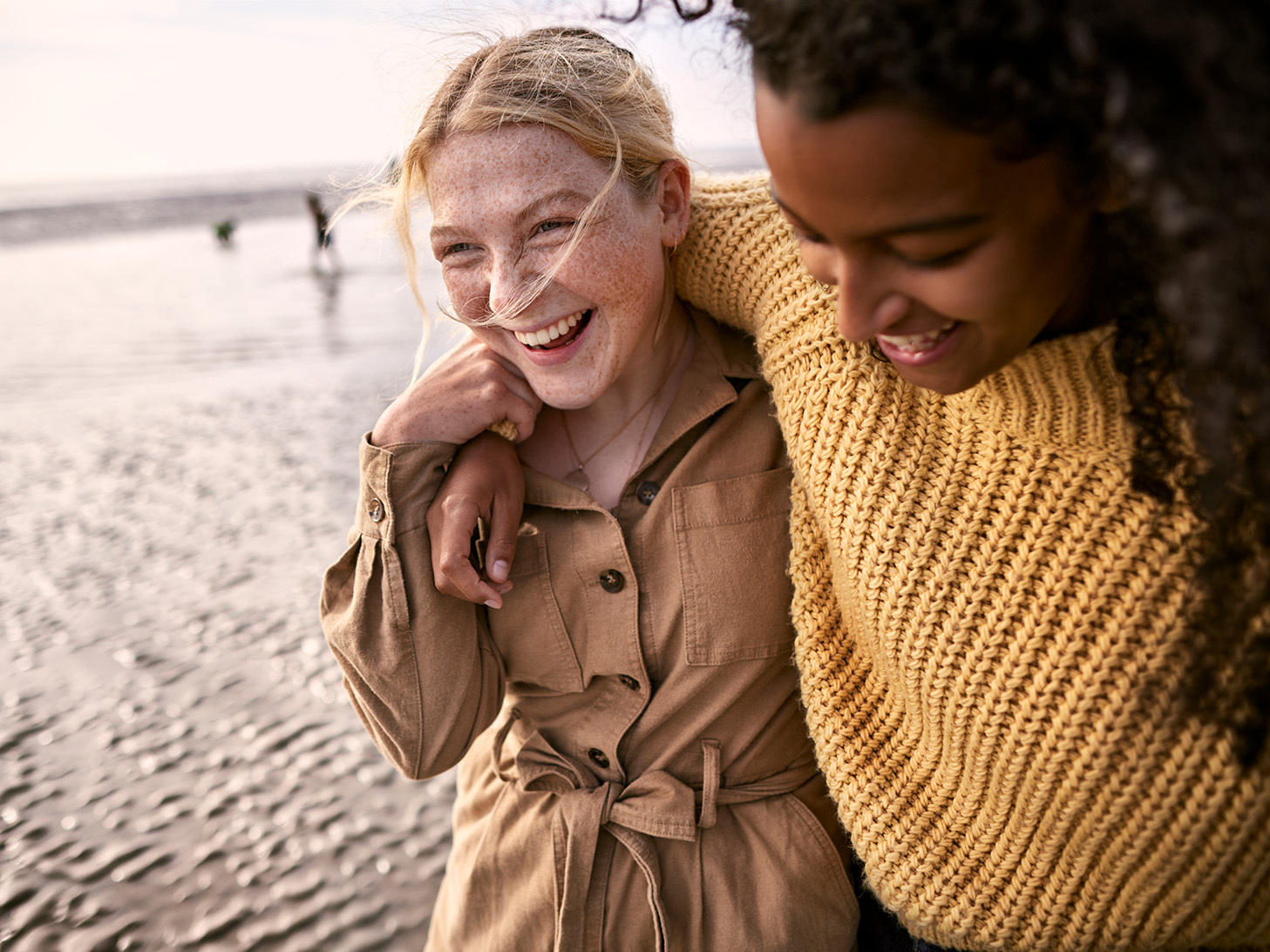 Two girls at the beach dressed warmly.