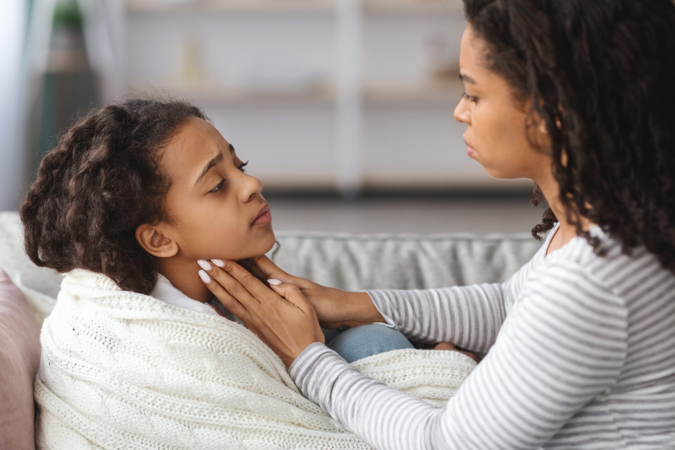 A mom caring for her sick daughter with a sore throat