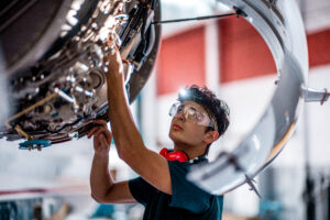 Aviation mechanic working on a plane engine in a hangar